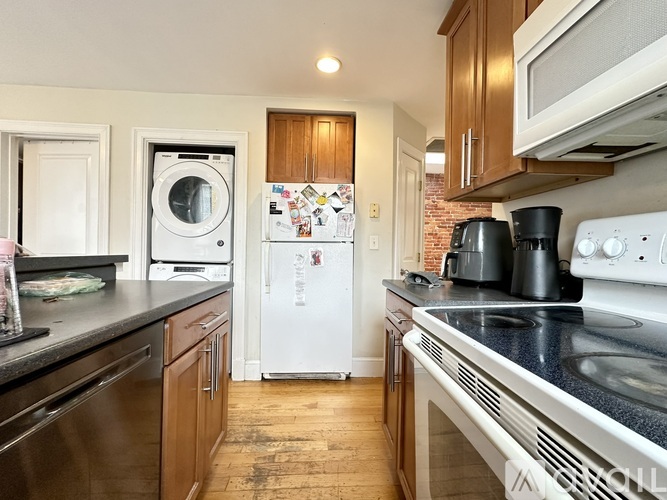 A kitchen with a white fridge and black countertops.