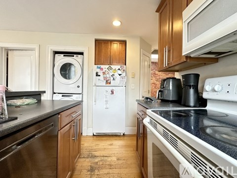 A kitchen with a white fridge and black countertops.