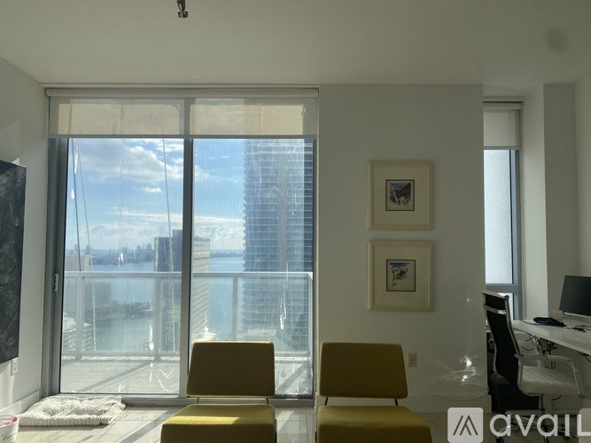 A room with a yellow chair and a window overlooking a cityscape.