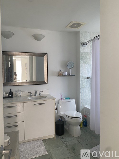 A bathroom with a toilet, sink, mirror, and a shower curtain.