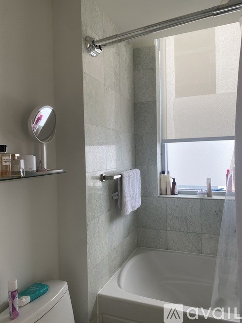 A white bathroom with a toilet, a mirror, and a bathtub.