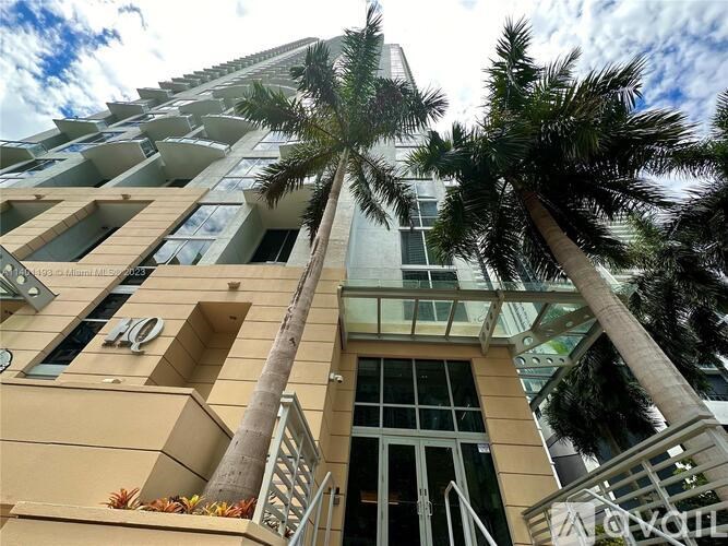 A tall building with a balcony and a palm tree in front.