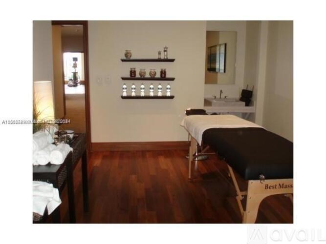 A massage table is set up in a room with wooden floors and a mirror on the wall.