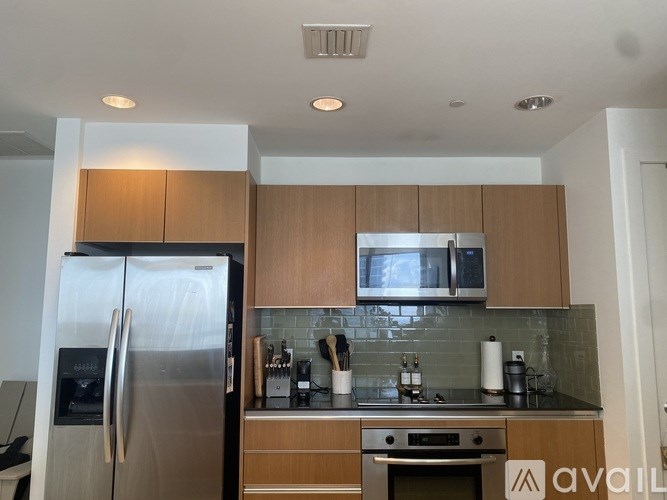 A kitchen with a stainless steel refrigerator and wooden cabinets.