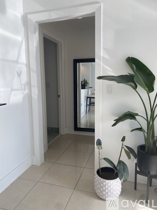 A white vase with a plant in it is on a tiled floor.
