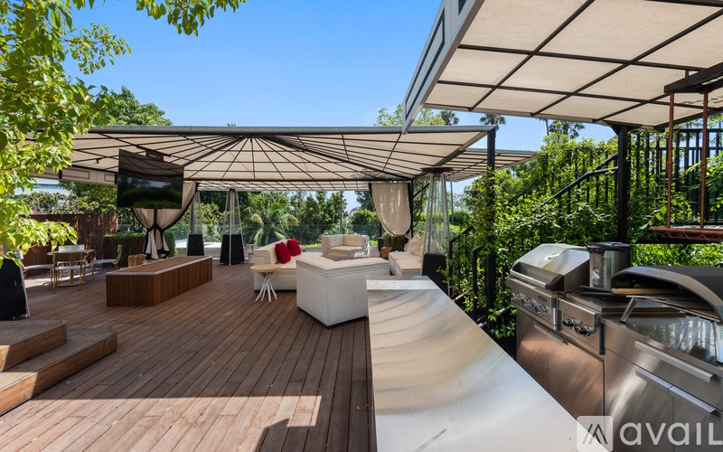A wooden deck with a white couch and a TV under a canopy.