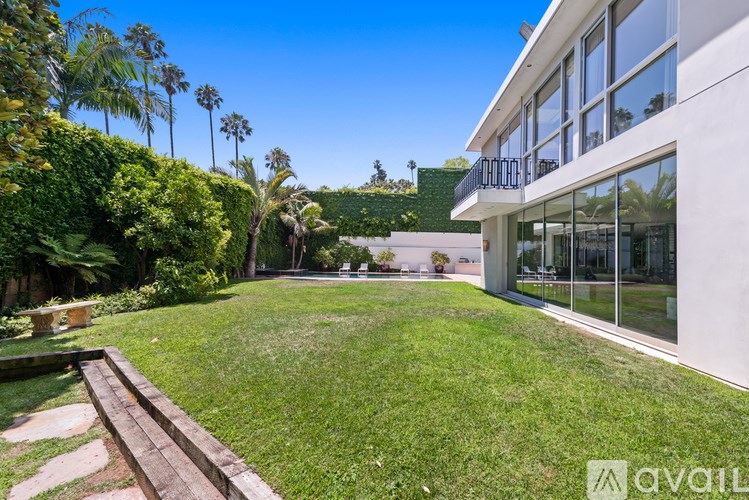 A modern house with a large backyard and a wooden deck.