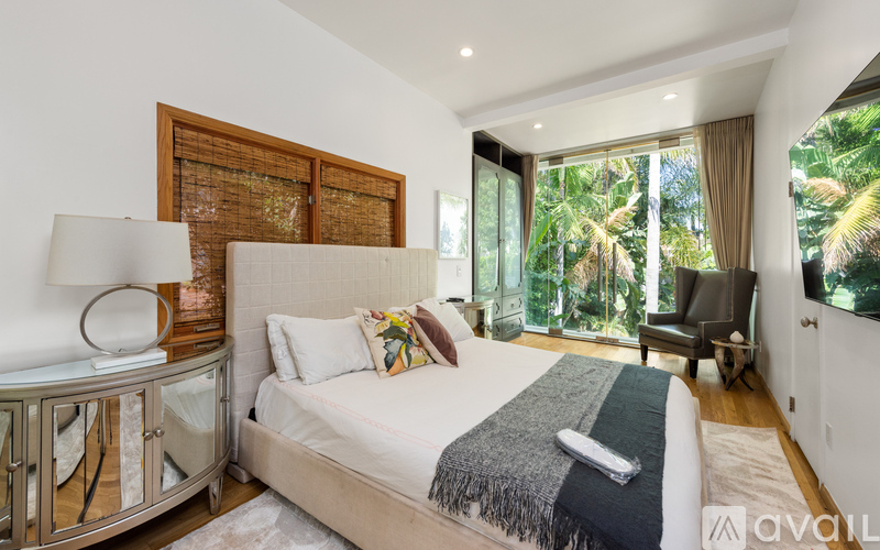 A bedroom with a large bed and a chair by the window.