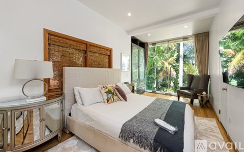 A bedroom with a large bed and a chair by the window.