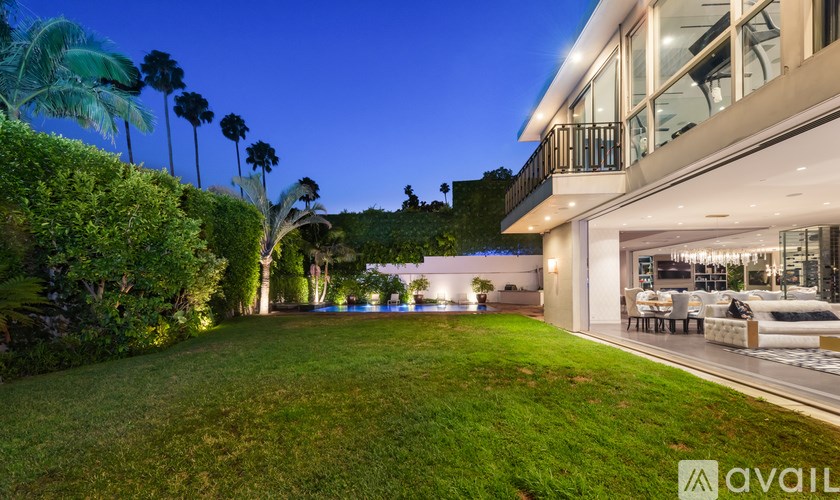 A modern house with a well-manicured lawn and palm trees in the background.
