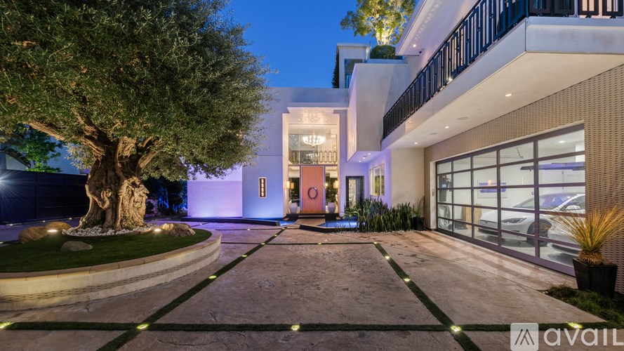 A modern house with a tree in front and a driveway leading to the entrance.