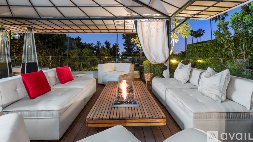 A patio with white couches and a lit fire pit.