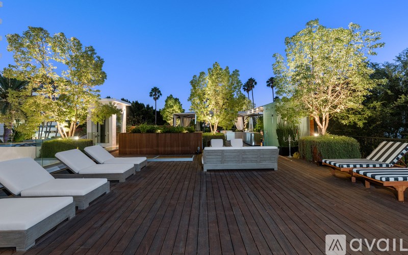 A wooden deck with lounge chairs and trees in the background.
