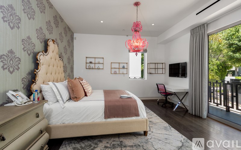 A bedroom with a large bed, a chandelier, and a balcony.