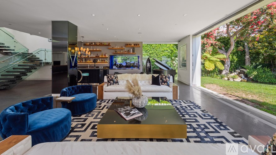 A modern living room with a blue and white patterned rug, a coffee table, and a staircase.