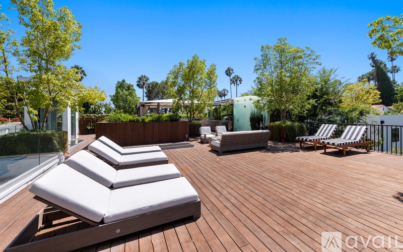 A wooden deck with sun loungers and trees in the background.