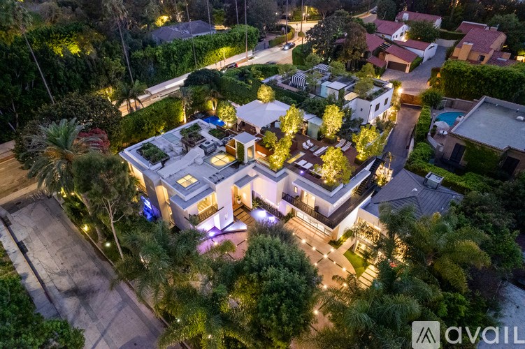 A large house with a swimming pool surrounded by trees and bushes.