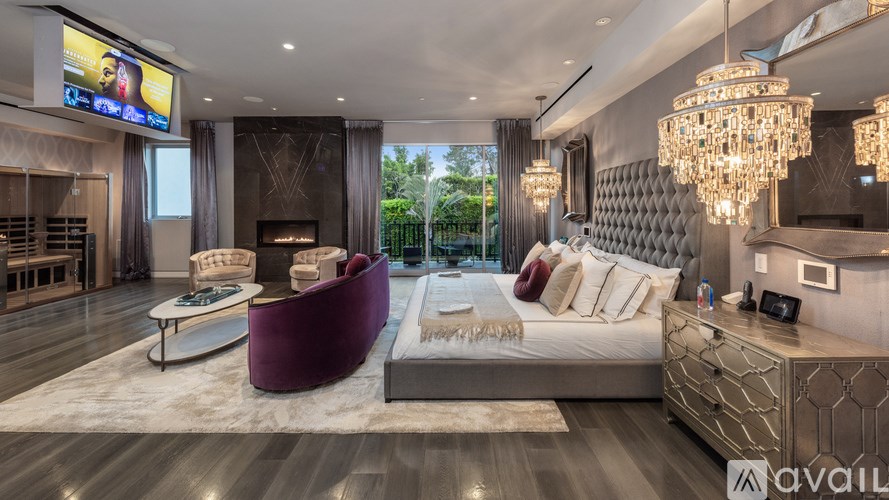 A modern bedroom with a large bed, a purple armchair, and a chandelier.