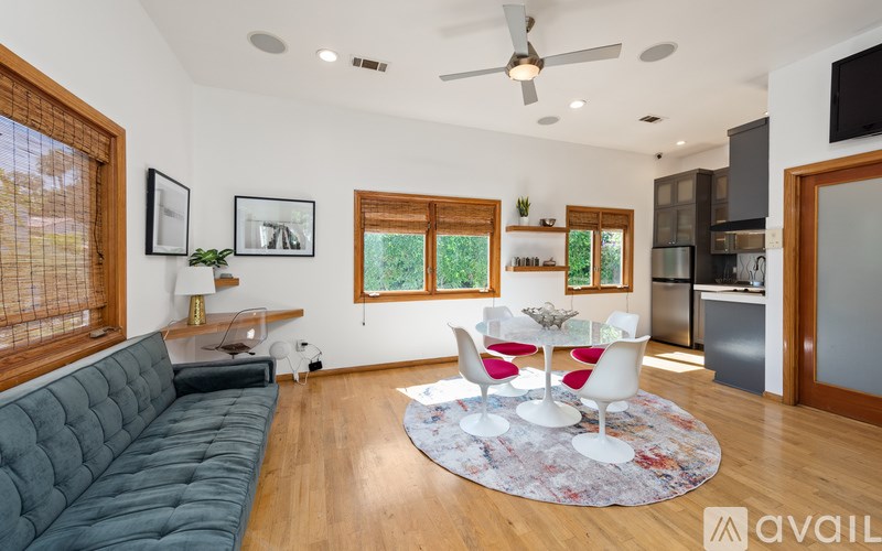 A living room with a grey sofa and a round rug with a white table and chairs in front of it.