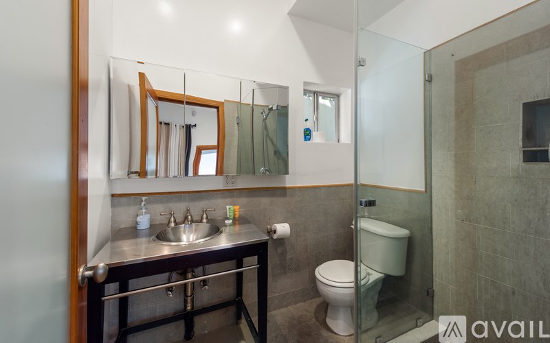 A bathroom with a sink, mirror, toilet and shower.