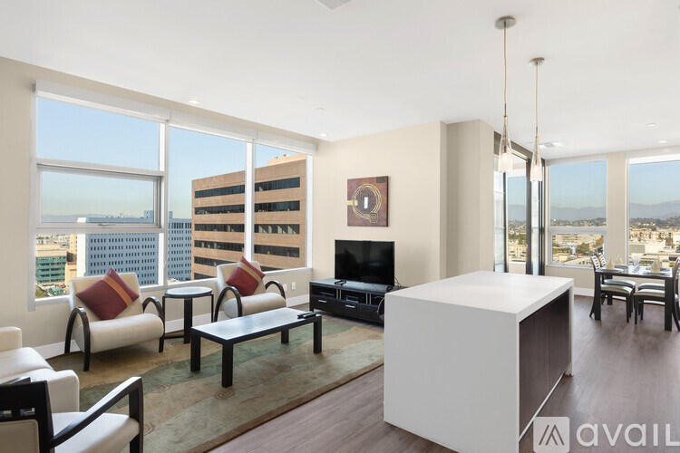 A living room with a white sofa, a black coffee table, and a TV on the wall.