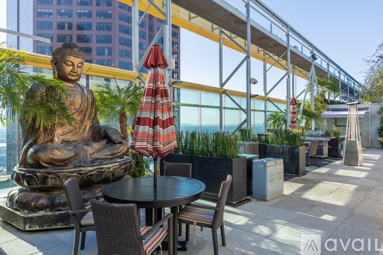 A statue of Buddha sits in the middle of a patio with tables and chairs.