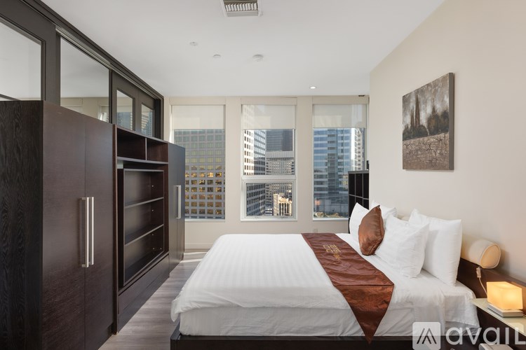 A bedroom with a large bed and a city view through the window.