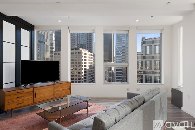 A living room with a grey couch and a wooden cabinet with a flat screen TV on top.