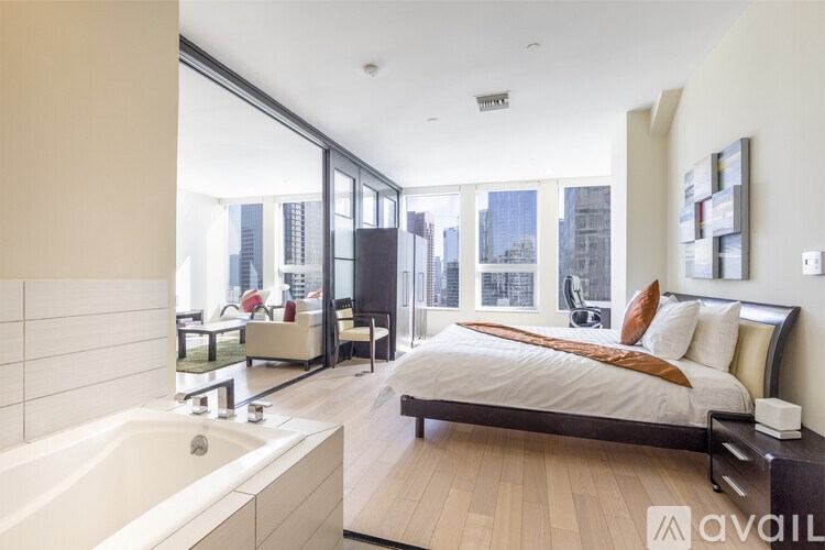 A modern bedroom with a large bed and a bathtub.