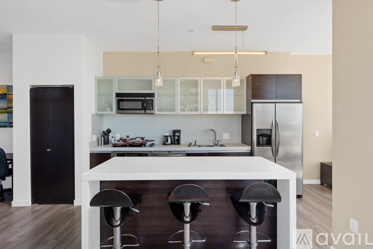 A kitchen with a white island and bar stools.
