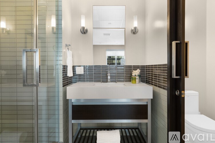 A bathroom with a white sink and a glass shower stall.