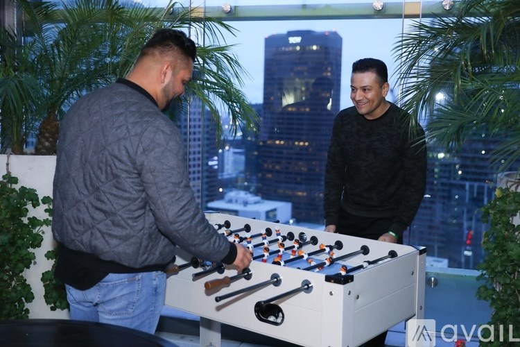 Two men playing a game of foosball on a table with a cityscape in the background.