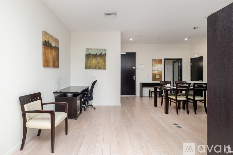 A room with a desk, chairs and a painting on the wall.