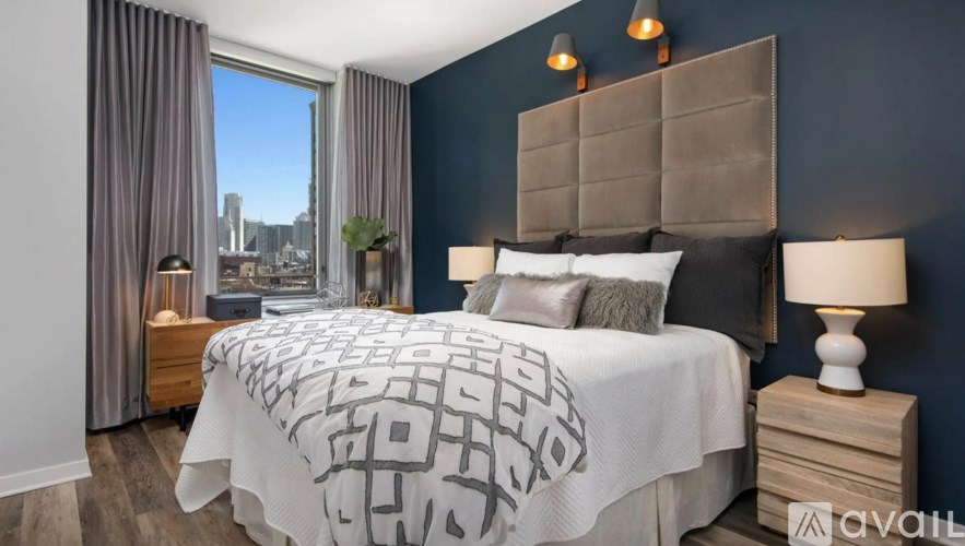 A bedroom with a large bed and a window overlooking a cityscape.