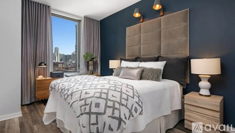 A bedroom with a large bed and a window overlooking a cityscape.
