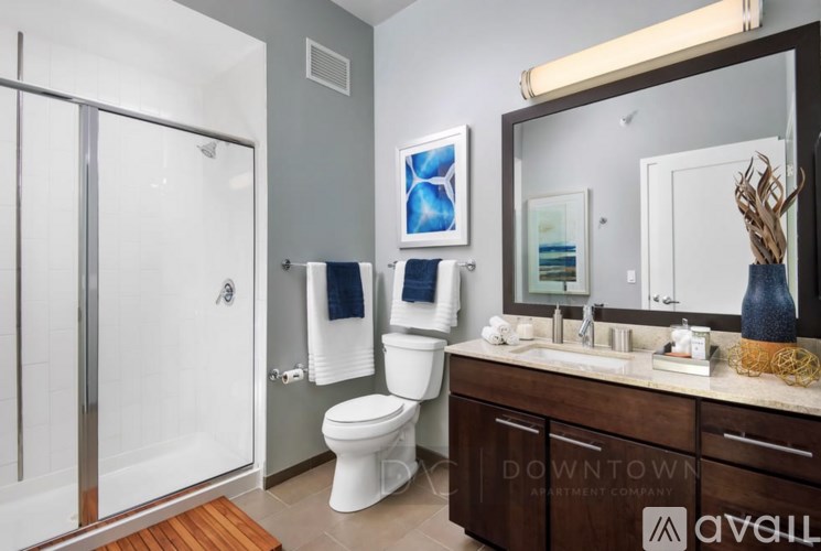 A bathroom with a toilet, sink, mirror, and shower.