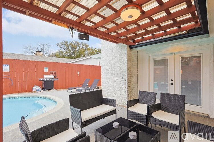 A patio with a table, chairs, and a pool.