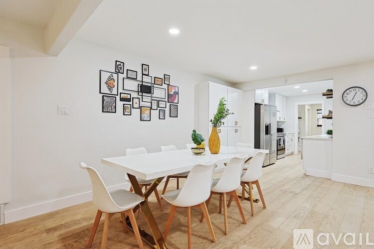 A dining room with a white table and chairs.