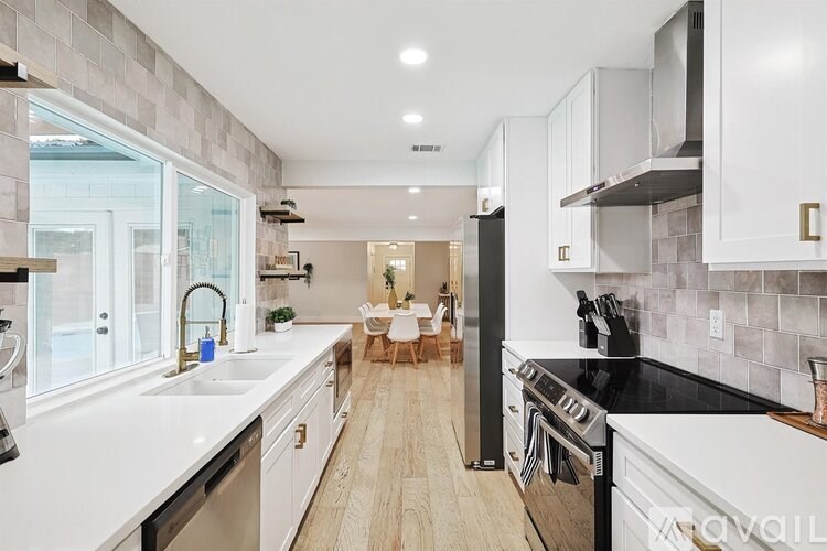 A modern kitchen with white cabinets and a black stove top oven.
