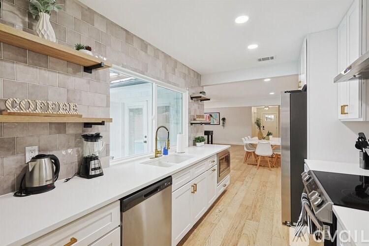 A modern kitchen with white cabinets and a wooden floor.