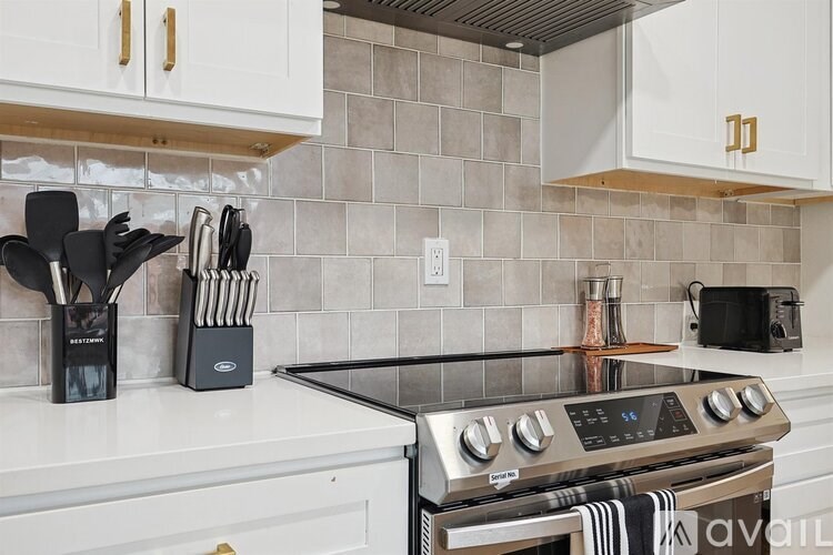 A kitchen with a stove top oven and white cabinets.