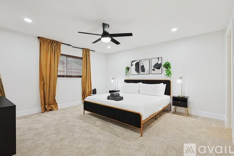 A bedroom with a large bed, a ceiling fan, and a window with curtains.
