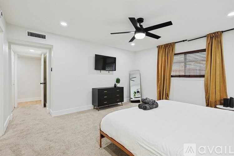 A bedroom with a bed, dresser, and television.