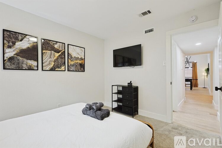A bedroom with a bed, a TV, and a painting on the wall.