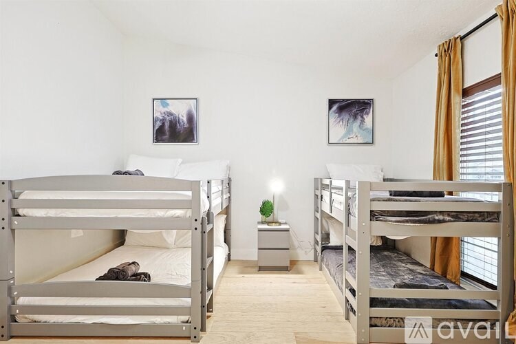 A room with two bunk beds and a small nightstand with a lamp.