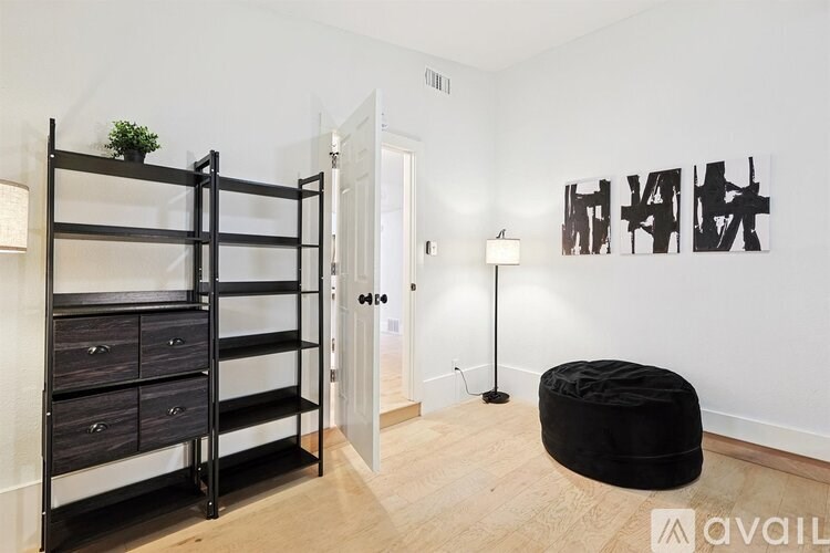 A black bunk bed with drawers is in a room with a white wall and a black bean bag chair.