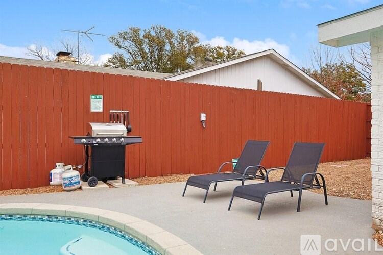 A poolside area with two chairs and a grill.