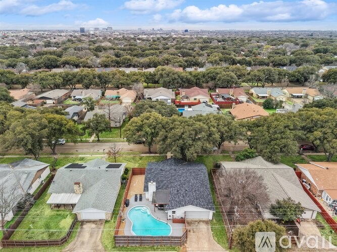 A bird's eye view of a residential area with houses, a swimming pool, and a tennis court.