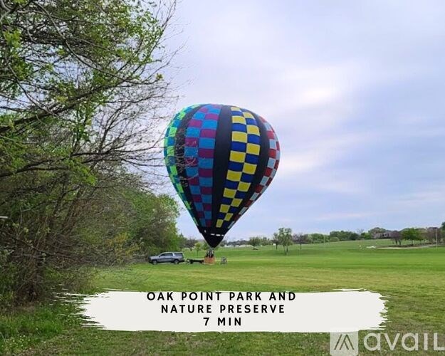 A hot air balloon with a checkerboard pattern floats over a field.
