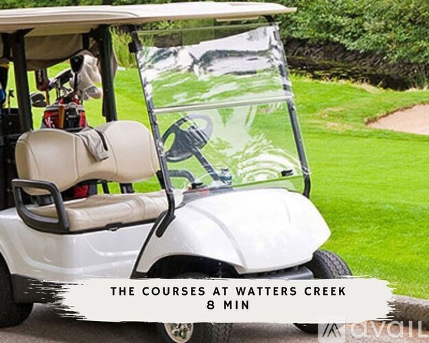 A white golf cart with a driver inside and a bag of clubs on the back.